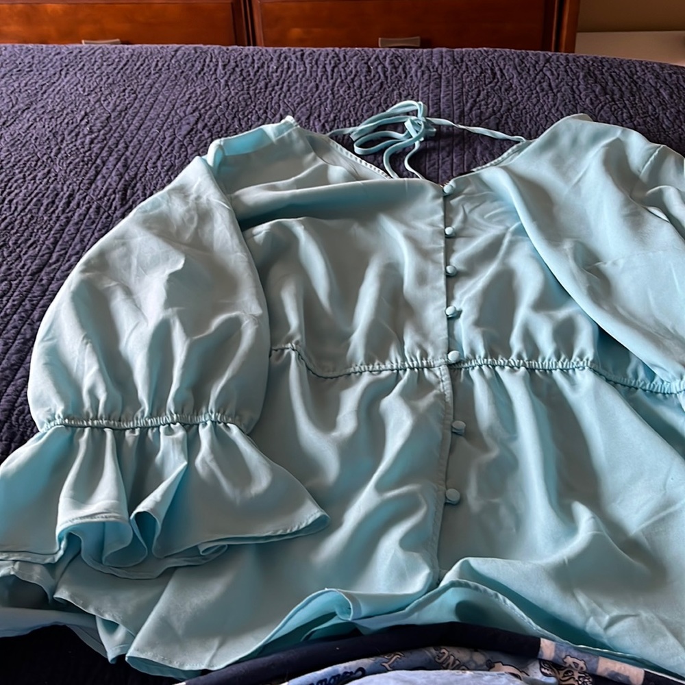 Beautiful light blue peplum top with flowing sleeves and back tie detail.